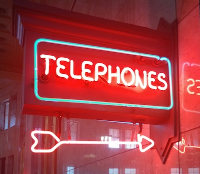 Neon Telephones sign with an arrow, representing the importance of having a dedicated business phone number