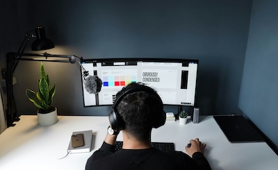 Freelancer wearing headphones working at a desk with a monitor and microphone, representing separating personal and business calls