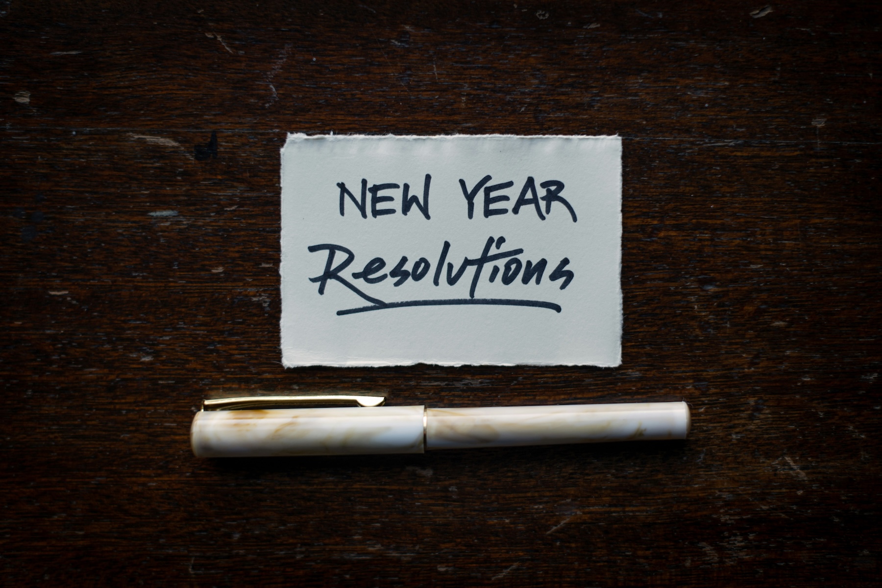 Handwritten New Year Resolutions note with a fountain pen on a wooden table, representing the deadline for business phone line migration