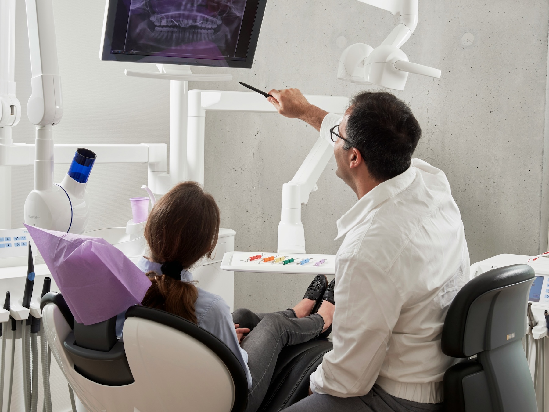 Dentist showing a patient an X-ray on a screen during a consultation, representing UK dental practices