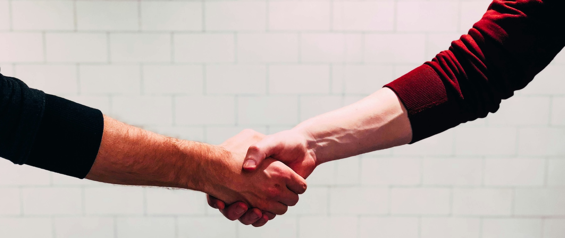 Two people shaking hands near a white painted wall, representing increased customer enquiries from local phone numbers