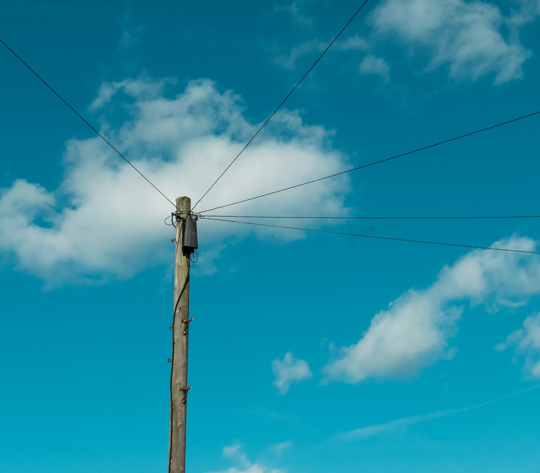 Wooden telephone pole with wires against a blue sky, representing traditional phone infrastructure you no longer need for a business line
