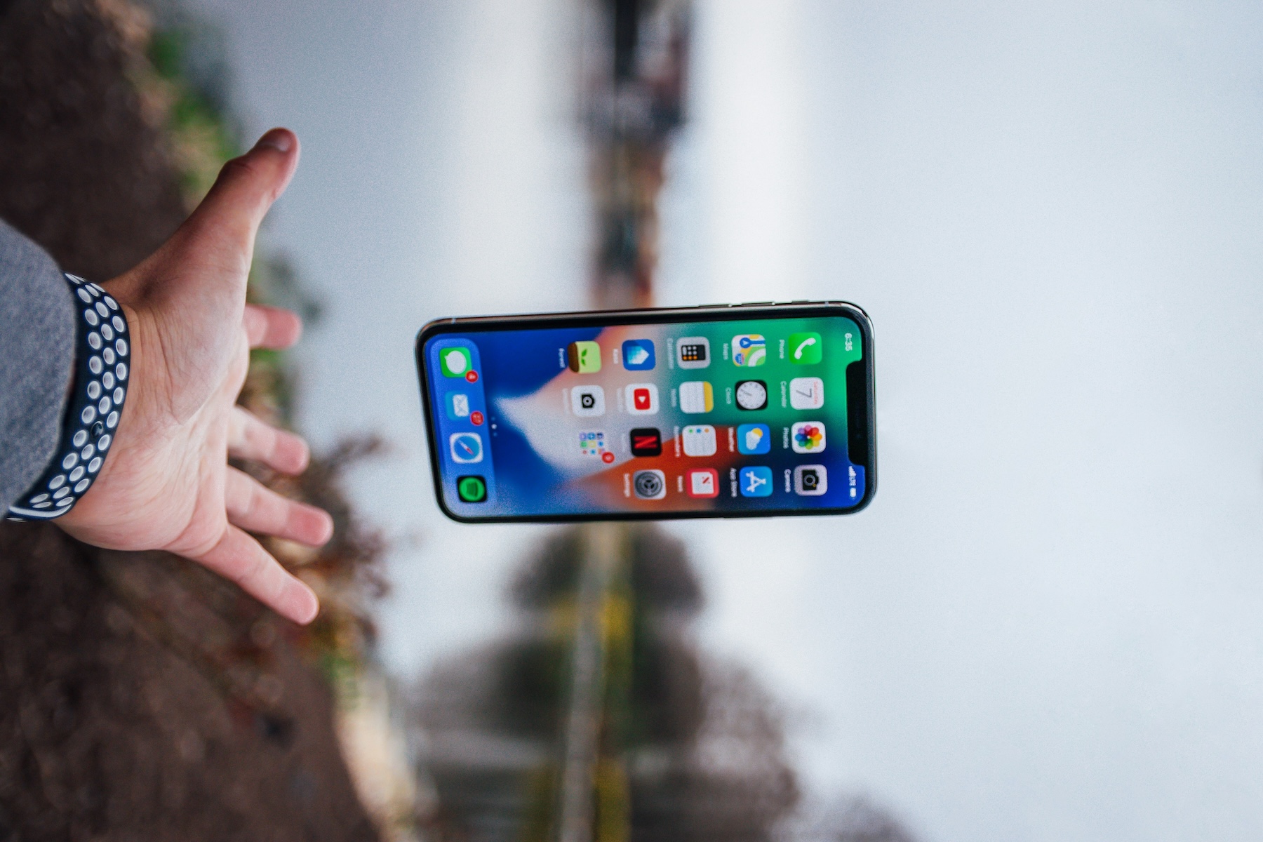 Hand releasing a smartphone into the air outdoors, representing a business that has outgrown its mobile phone number