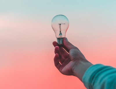 Hand holding a light bulb against a pastel sky, representing bright ideas for marketing campaign call tracking