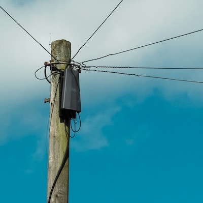 Wooden telephone pole with wires against a blue sky, representing traditional phone infrastructure you no longer need for a business line