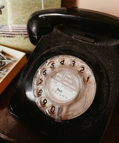 Traditional rotary telephone next to a modern smartphone, representing the comparison between landlines and virtual phone numbers