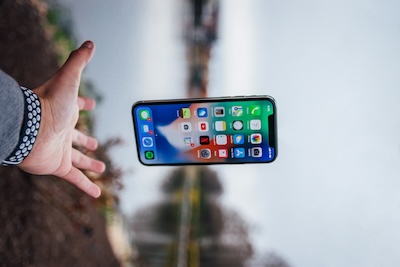 Hand releasing a smartphone into the air outdoors, representing a business that has outgrown its mobile phone number