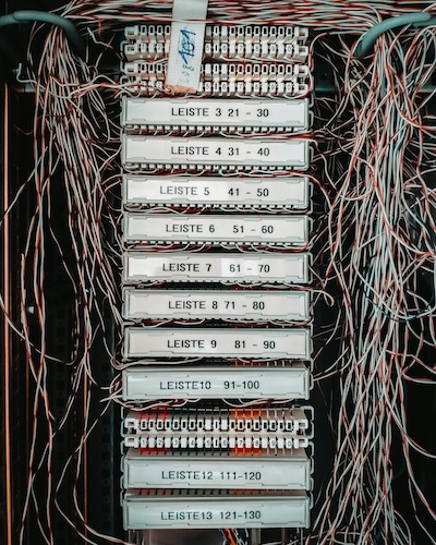 Telephone exchange patch panel with numbered terminal strips and coloured wiring, representing the copper PSTN network being switched off