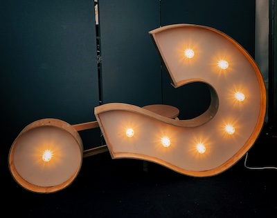 Large illuminated marquee question mark, representing the question of whether businesses should use multiple local numbers across the UK