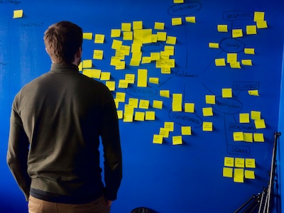 Man standing in front of a wall covered in yellow sticky notes, representing startup planning and business phone system decisions