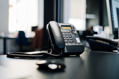 A desk phone on a table, representing the choice between traditional landlines and virtual phone numbers for startups